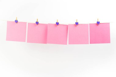 Beyaz arka planda izole clothespins ile clothesline pembe çıkartmalar. Metniniz için yer.