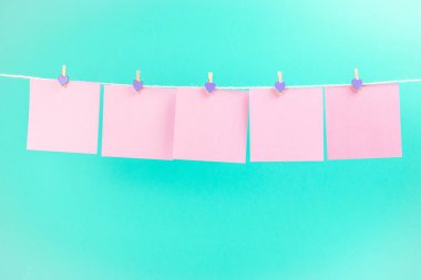 Mavi arka planda izole clothespins ile clothesline üzerinde pembe çıkartmalar. Metniniz için yer.