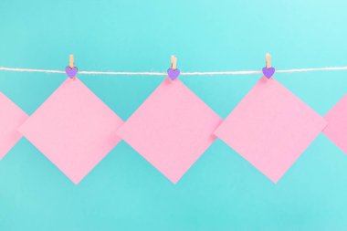 Mavi arka planda izole clothespins ile clothesline üzerinde pembe çıkartmalar. Metniniz için yer.