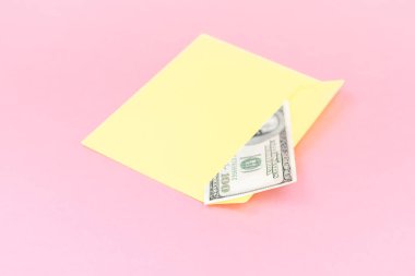 Sarı zarf içinde para yakın pastel pembe arka plan üzerinde yatıyor. Markalama alay; pembe arka planda ön görünüm. 