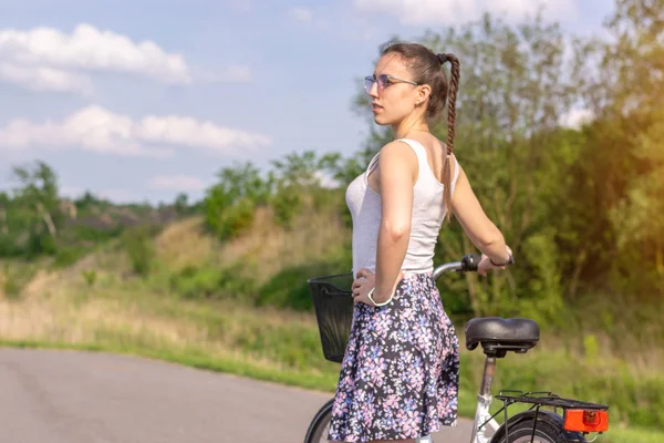 Active life. A woman with a bike enjoys the view at summer forest. Bicycle and ecology lifestyle concept.