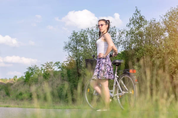 Active life. A woman with a bike enjoys the view at summer forest. Bicycle and ecology lifestyle concept.