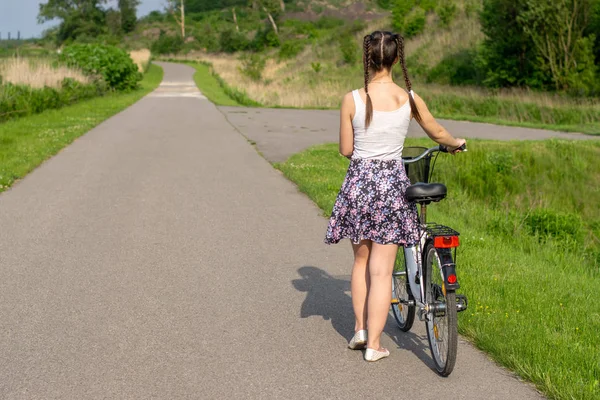 Active life. A woman with a bike enjoys the view at summer forest. Bicycle and ecology lifestyle concept.