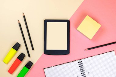 Tablet, okul malzemeleri, defter ve pastel pembe ve bej arka plan renkli işaretleri. Marka kırtasiye maket sahnesi, tasarımınızı yerleştirmek için boş nesneler.