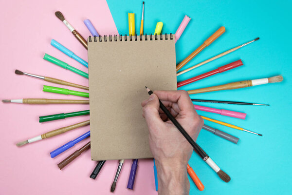 Male hand drawing, blank paper and colorful pencils. Branding stationery mockup scene, blank objects for placing your design. Concept: preparing for school.