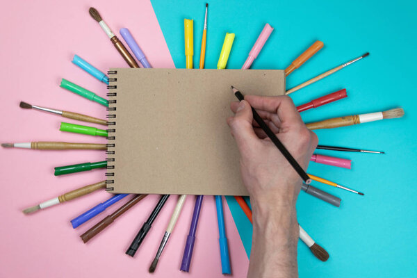 Male hand drawing, blank paper and colorful pencils. Branding stationery mockup scene, blank objects for placing your design. Concept: preparing for school.