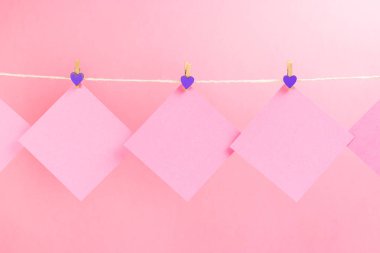 Pembe arka planda izole clothespins ile clothesline üzerinde pembe çıkartmalar. Metniniz için yer.