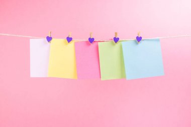 Renkli kağıt kartları pembe arka plan üzerinde izole ip asılı. Metniniz için yer.