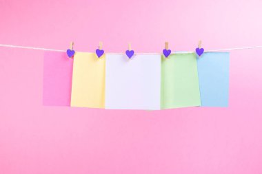 Renkli kağıt kartları pembe arka plan üzerinde izole ip asılı. Metniniz için yer.