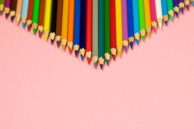 Pembe arka plan üzerinde izole kopya alanı ile renkli kalem. Eğitim çerçevesi kavramı.