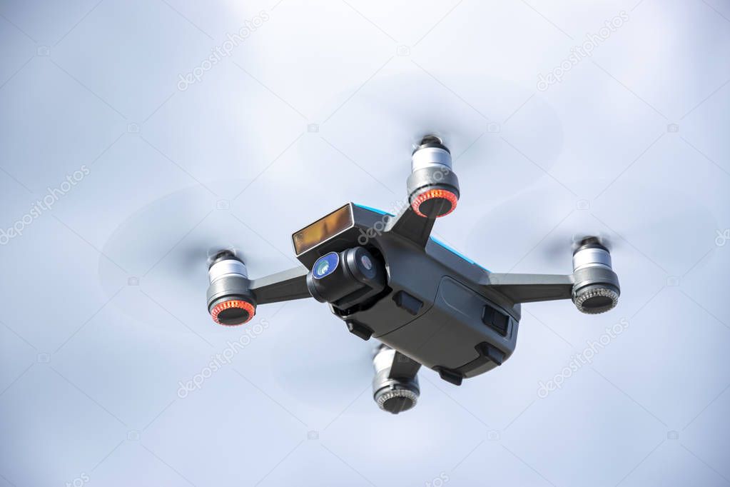Drone flying overhead in cloudy blue sky 