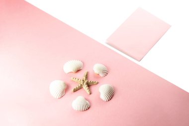 Düz üst görünüm Pembe zarf, pembe bir arka plan üzerinde deniz kabukları yatıyordu. Yaz tropikal tatil arka plan. 