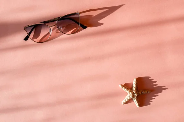 Moderne elegante zonnebrillen en seastar op trendy roze papieren achtergrond in zonlicht. Vakantie-en feest concept met ruimte voor tekst. Tropische zomer vakantie — Stockfoto