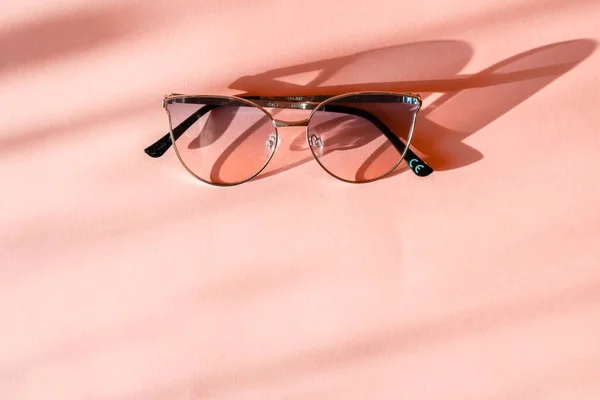 Moderne elegante Sonnenbrille mit Metallrahmen auf trendigem rosa Papierhintergrund im Sonnenlicht. flach lag. kreativer Kontrast Sommerbild. Urlaub und Party-Konzept. Raum für Text. Tropische Sommerferien — Stockfoto