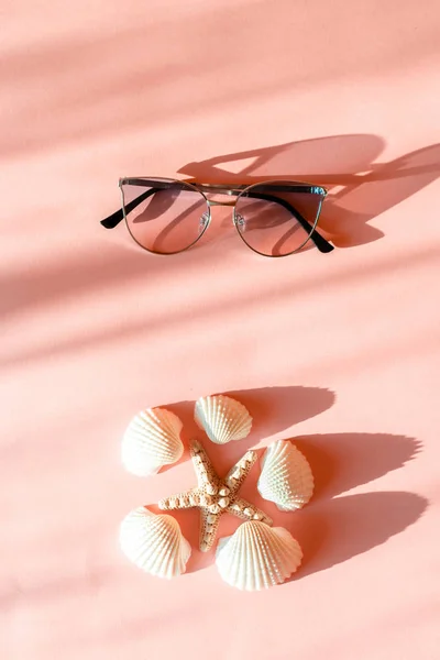 Lunettes de soleil Seastar, coquillage et modernes élégantes sur fond de papier rose tendance à la lumière du soleil. Tropical vacances d'été concept avec espace pour le texte. Pose plate . — Photo