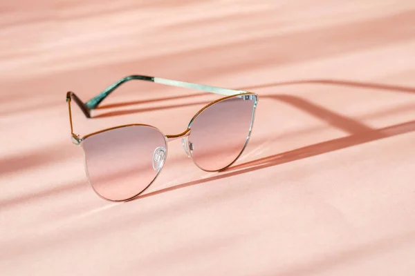 Moderne elegante Sonnenbrille mit Metallrahmen auf trendigem rosa Papierhintergrund im Sonnenlicht. flach lag. kreativer Kontrast Sommerbild. Urlaub und Party-Konzept. Raum für Text. Tropische Sommerferien — Stockfoto