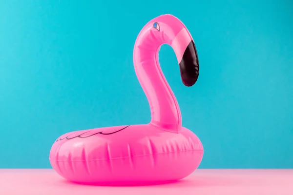 Aufblasbarer Mini-Flamingo auf pastellblauem und rosa Hintergrund. Pool-Float-Party, trendiges Sommerkonzept. flache Lage, Kopierraum. — Stockfoto