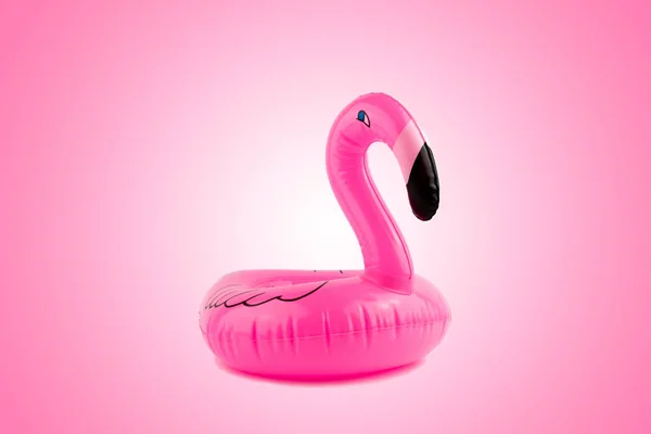 Pink, trendy, blown beach flamingo on a pink background. Summer beach composition.