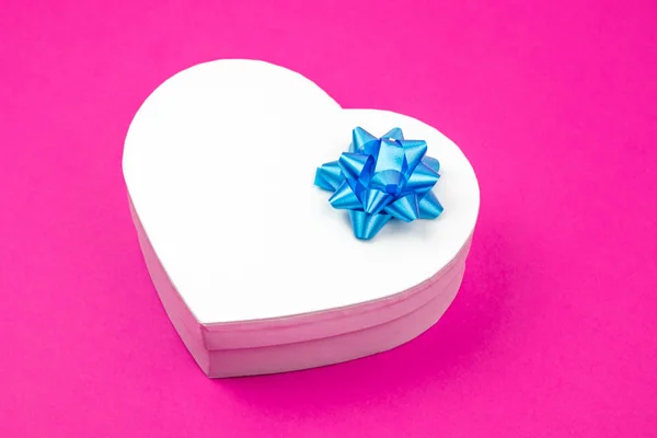 Cutie cadou în formă de inimă cu arc albastru pe un fundal roz. Mock up. Un loc gol pentru o inscripţie. Cadou pentru Crăciun, mulțumiri pentru zi, sărbători de ziua de naștere . — Fotografie, imagine de stoc