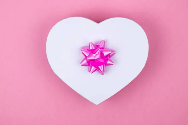 Pudełko na prezent w kształcie serca z różowym kokardą na różowym tle. Makiety. Pocztówka na wakacje. Puste miejsce na napis. — Zdjęcie stockowe
