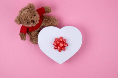Oyuncak ayı, kırmızı yay ile şekillenmiş beyaz kutu kalpler, Sevgililer Günü hediyesi . Noel için hediye, teşekkür veren gün, doğum günü tatili. 