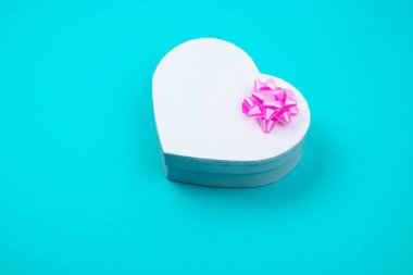 Tatil için pembe yay ile beyaz kalp şeklinde hediye kutusu, noel, teşekkür gün veren, doğum günü üst görünümü mavi arka plan izole. 