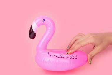 Pembe arka planda izole kadın elinde Mini pembe flamingo. Yaz plaj kompozisyonu. Düz döşeme, kopyalama alanı.