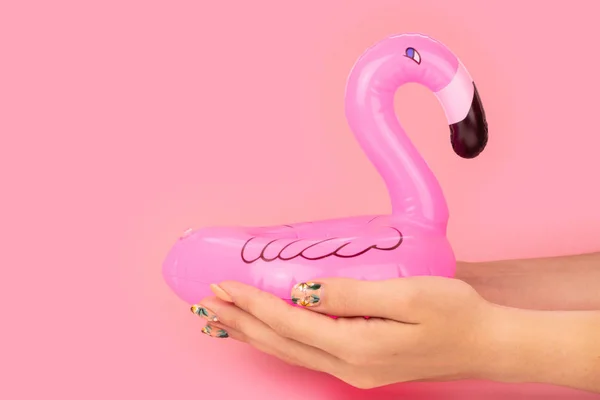 Mini-rosa Flamingo in Frauenhänden isoliert auf rosa Hintergrund. Sommerstrandkomposition. flache Lage, Kopierraum. — Stockfoto