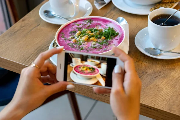 Smartphone fotografía de alimentos sopa de zanahoria en un tazón. Las manos femeninas toman la foto telefónica de la cena o el almuerzo para las redes sociales. Comida sana vegetariana vegana cruda —  Fotos de Stock