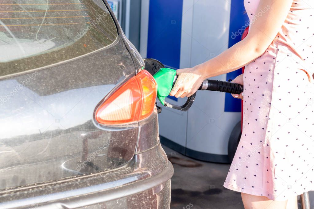 Woman fills petrol into her car at a gas station closeup