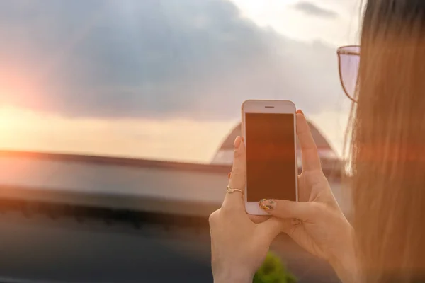 A rapariga faz uma foto ao telefone ao pôr-do-sol. Conceito de viagem — Fotografia de Stock