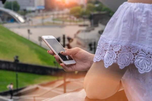 Woman typing write message on smartphone at sunset. Cropped image of young pretty girl with smartphone. — Stock Photo, Image