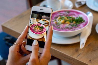 Smartphone gıda fotoğraf kase havuç çorbası. Kadın elleri sosyal ağlar için akşam yemeği veya öğle yemeği telefon fotoğrafı çekmek. Çiğ vegan vejetaryen sağlıklı gıda