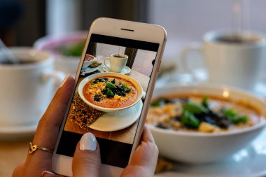 Genç kadın elleri kabak ve havuç çorbası fotoğraf yapmak. Sosyal ağlar akıllı telefon gıda fotoğrafçılığı alın. Çiğ vegan vejetaryen sağlıklı gıda