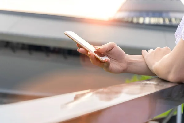 Woman typing write message on smartphone at sunset. Cropped image of young pretty girl with smartphone. — Stock Photo, Image