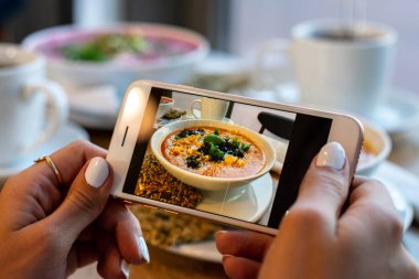 Genç kadın elleri kabak ve havuç çorbası fotoğraf yapmak. Sosyal ağlar akıllı telefon gıda fotoğrafçılığı alın. Çiğ vegan vejetaryen sağlıklı gıda
