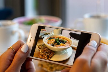 Genç kadın elleri kabak ve havuç çorbası fotoğraf yapmak. Sosyal ağlar akıllı telefon gıda fotoğrafçılığı alın. Çiğ vegan vejetaryen sağlıklı gıda