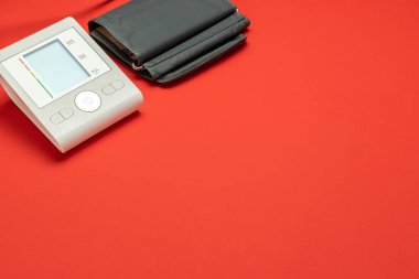 Tansiyon testi. Kırmızı zemin üzerindeki kan basıncını kontrol etmek için sphygmomanometre monitörüne bak. Doktor ve hasta için tıbbi sağlık testi hipertansiyonu. Hastane tanı teknolojisi.