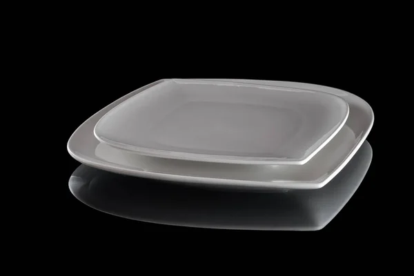 Feketén izolált ételek. Négyzet fehér üres tányér vacsora sötét háttérrel. Tiszta kör porcelán edények. Reggeli asztali eszközök. — Stock Fotó