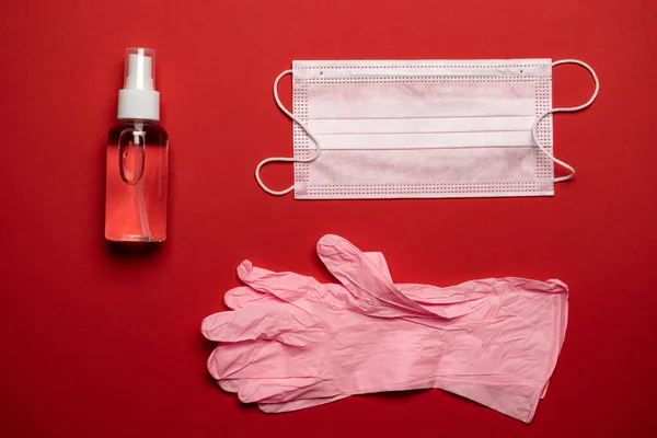 Virus background. Protection mask, sanitizer gel, lab gloves - medical equipment on red background. Concept coronavirus COVID quarantine. Wuhan epidemic outbreak.