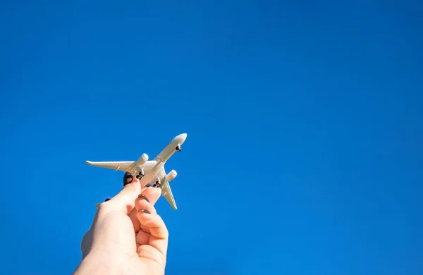 太陽の光の日におもちゃを遊んでいる子供たち 手の中の白い飛行機は青い日差しの空を飛ぶ 飛行機 航空機の飛行明るい背景にあります 旅行のコンセプト — ストック写真