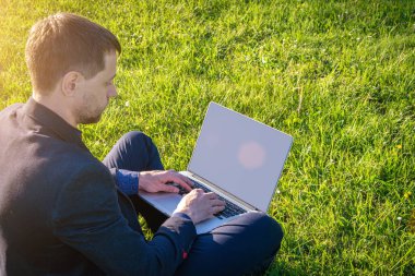 İş dışarıda. Öğrenci çocuk dizüstü bilgisayarla, bilgisayar tabletleriyle yaz parkında çalışıyor. Çevrimiçi teknoloji ve açık hava adamı. Ofis uzaklığı eğitim kavramından kaçmış..