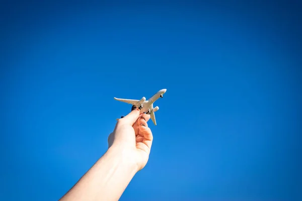 太陽の光の背景に飛行機の白いおもちゃ 女性の手で明るい飛行機は太陽の光の空を旅する 航空機のコンセプトで飛ぶ — ストック写真
