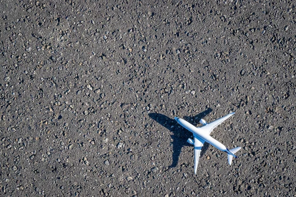 暗いアスファルトの背景に飛行機の白いおもちゃ 明るい飛行機 航空旅行のコンセプトで飛行航空機 コピースペース — ストック写真
