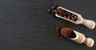 Kahvaltının arka planında kahve çekirdekleri. Bir fincan koyu espresso ya da içecek için. Çeşit çeşit öğütülmüş toprak ve kavrulmuş kahve çekirdekleri. Boşluğu kopyala, üst görünüm.