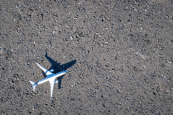 Flyvemaskine hvid legetøj på mørk asfalt baggrund. Lyse fly, flyve fly i flyrejser koncept. - Stock-foto