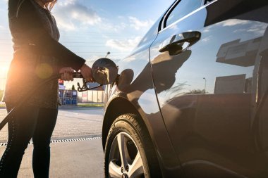 Benzin istasyonu. Depoya benzin pompala. Hortumda benzin yağı var. Elin ve yakıt silahının yakın çekimi. Bulanık arkaplan.
