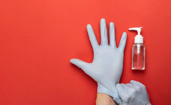 Ιστορικό ιατρικού εξοπλισμού. Τζελ απολυμαντικού ιατρικής αλκοόλης σε εργαστηριακά γάντια στο κόκκινο. Νόσος του Coronavirus. Διαυγές απολυμαντικό σε φιάλη αντλίας. Προληπτικά μέτρα για την προστασία από τον κορωναϊό — Φωτογραφία Αρχείου