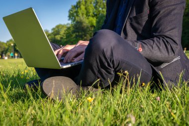 Bilgisayar açık havada. Öğrenci çocuk dizüstü bilgisayarda, tablet de yaz parkında çalışıyor. Çevrimiçi teknolojiyle insan işi doğası dışarıda. Elektronik aletler uzaklık öğrenme konsepti.