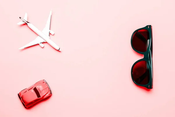 비행기 여행에 사용되는 고급 비행기 장난감이다. 하얀 비행기, 선글라스, 차 위쪽 시야의 밝은 핑크 배경에. 하늘을 배경으로 한 항공기. — 스톡 사진